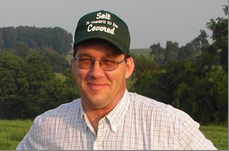 Jim Hoorman in a green cap standing in a field